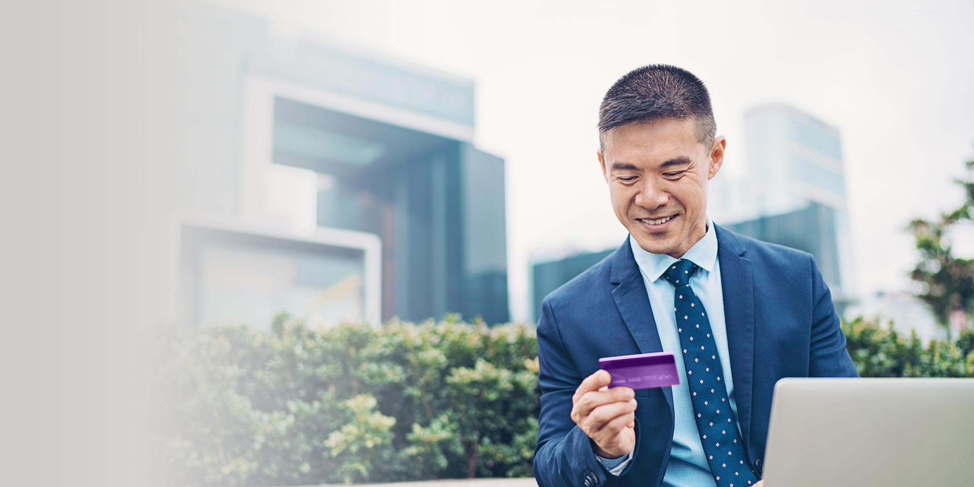 A businessman smiles as he looks at his mobile phone and explores Commercial Real Estate Financing options